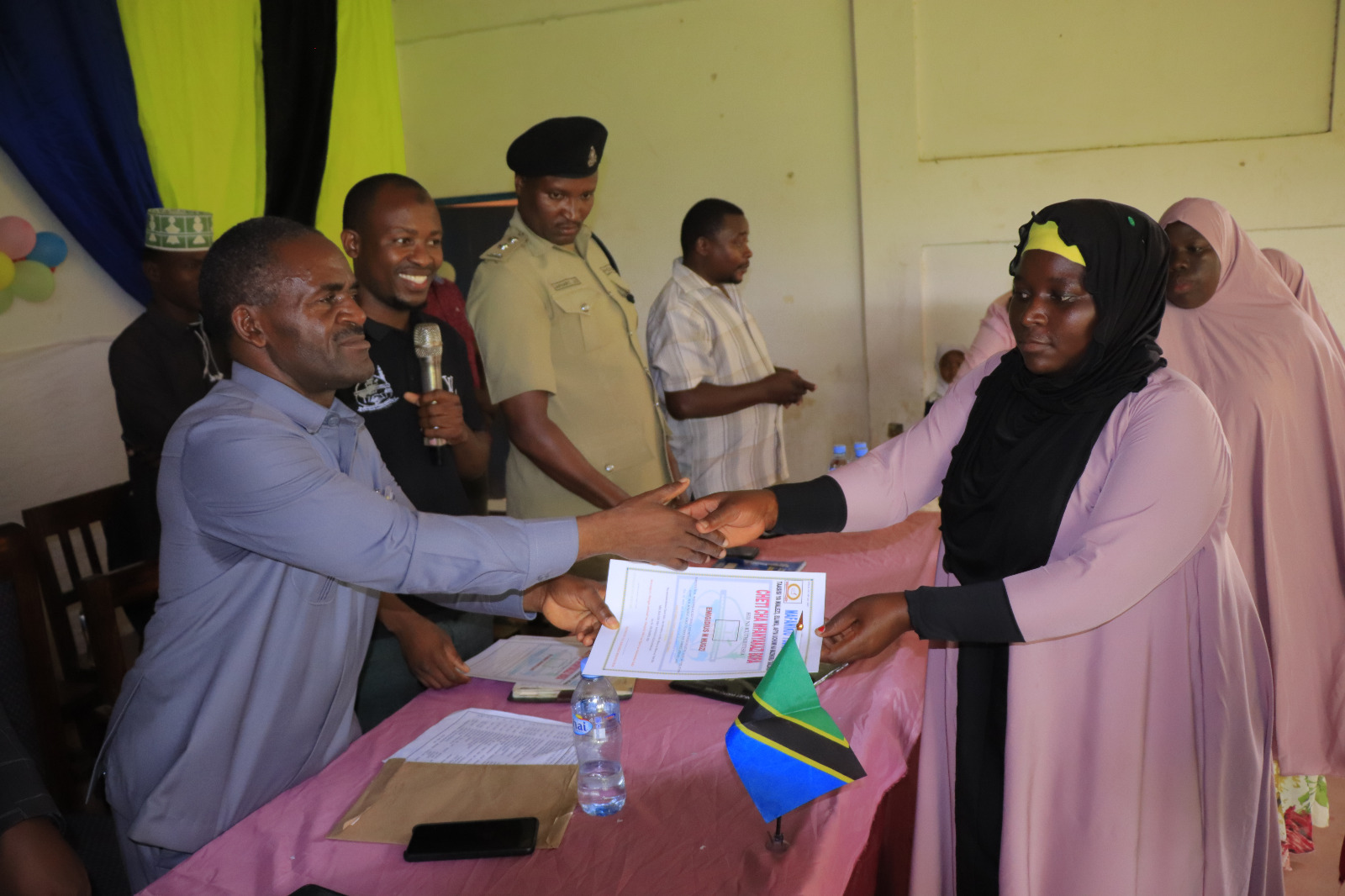 Photos of Mafanikio Foundation volunteers receiving certificates of honor from the Regional Education Officer of Tabora, Mr. Juma Japhet Kaponda, on behalf of the Regional Commissioner of Tabora, for successfully ensuring that all primary school graduates receive special training. Additionally, they launched the campaign "No Child Left Behind - Quality Education for All