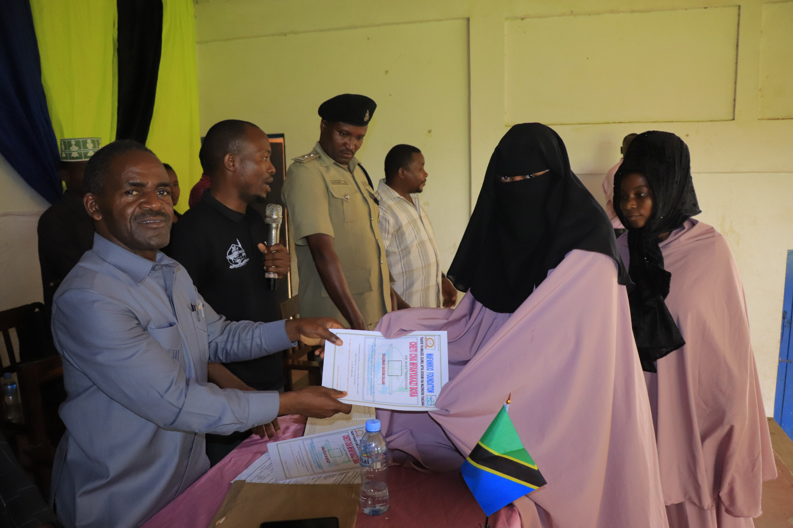 Photos of Mafanikio Foundation volunteers receiving certificates of honor from the Regional Education Officer of Tabora, Mr. Juma Japhet Kaponda, on behalf of the Regional Commissioner of Tabora, for successfully ensuring that all primary school graduates receive special training. Additionally, they launched the campaign "No Child Left Behind - Quality Education for All