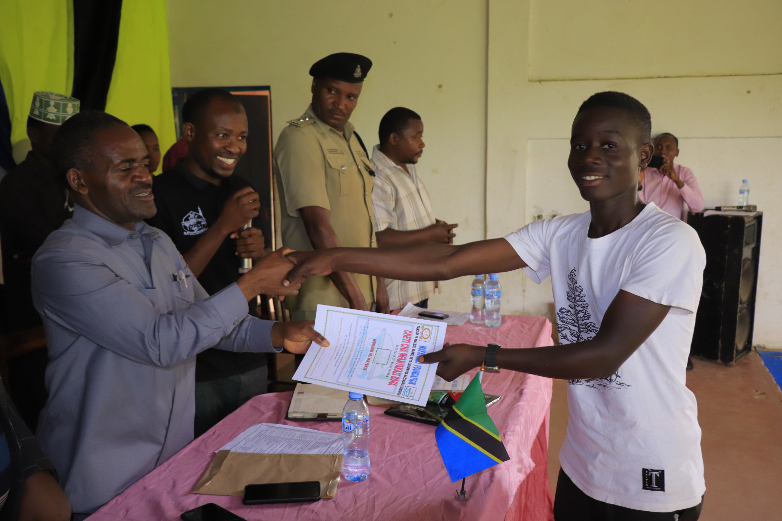 Photos of Mafanikio Foundation volunteers receiving certificates of honor from the Regional Education Officer of Tabora, Mr. Juma Japhet Kaponda, on behalf of the Regional Commissioner of Tabora, for successfully ensuring that all primary school graduates receive special training. Additionally, they launched the campaign "No Child Left Behind - Quality Education for All