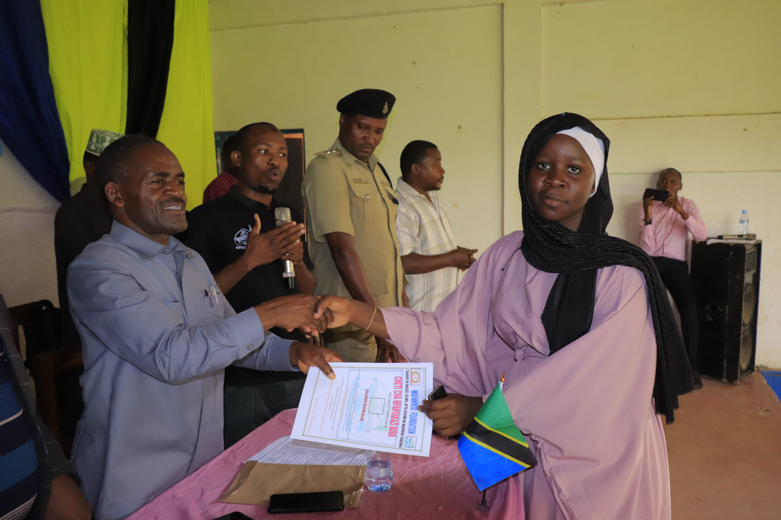 Photos of Mafanikio Foundation volunteers receiving certificates of honor from the Regional Education Officer of Tabora, Mr. Juma Japhet Kaponda, on behalf of the Regional Commissioner of Tabora, for successfully ensuring that all primary school graduates receive special training. Additionally, they launched the campaign "No Child Left Behind - Quality Education for All