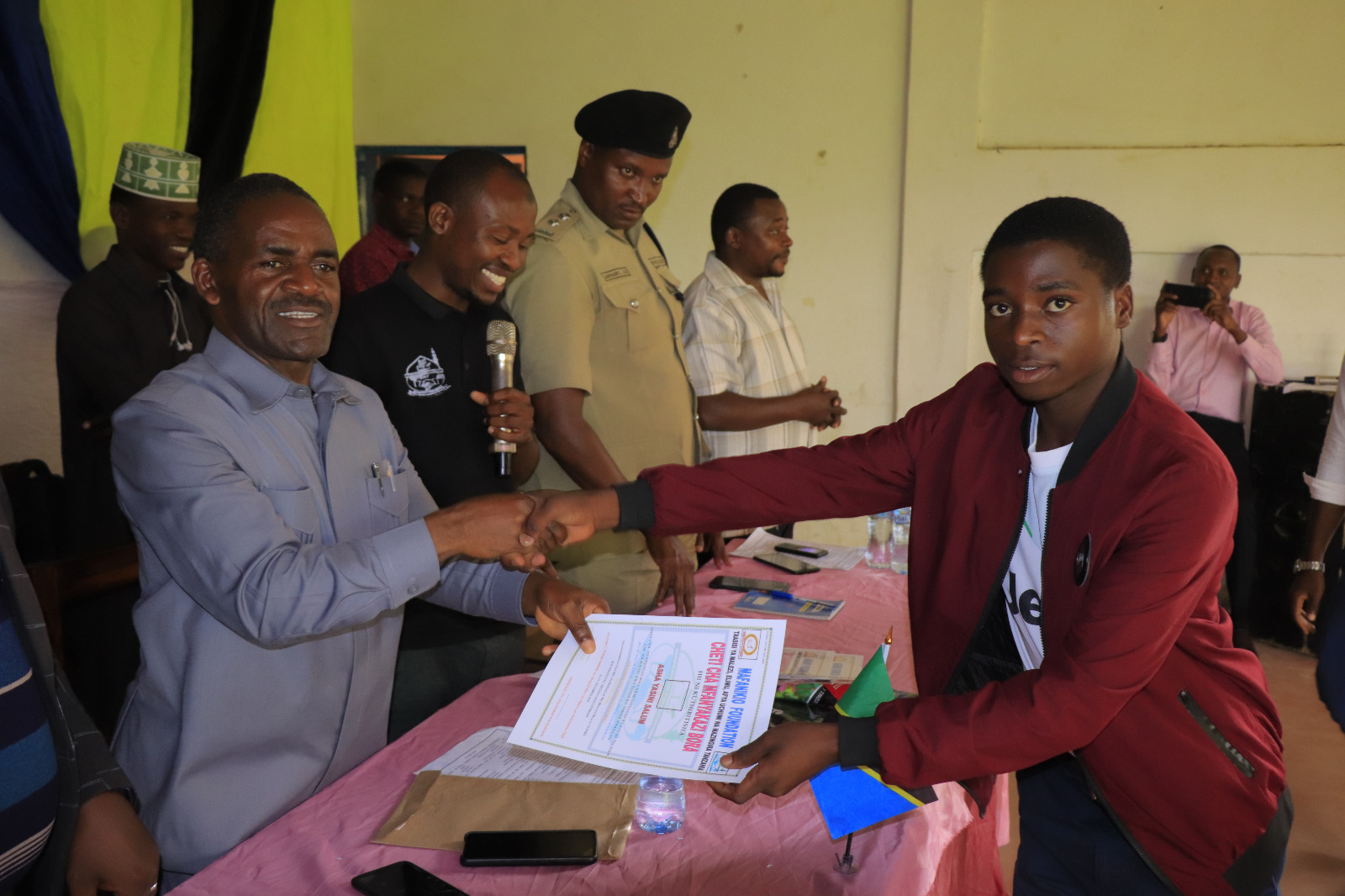 Photos of Mafanikio Foundation volunteers receiving certificates of honor from the Regional Education Officer of Tabora, Mr. Juma Japhet Kaponda, on behalf of the Regional Commissioner of Tabora, for successfully ensuring that all primary school graduates receive special training. Additionally, they launched the campaign "No Child Left Behind - Quality Education for All