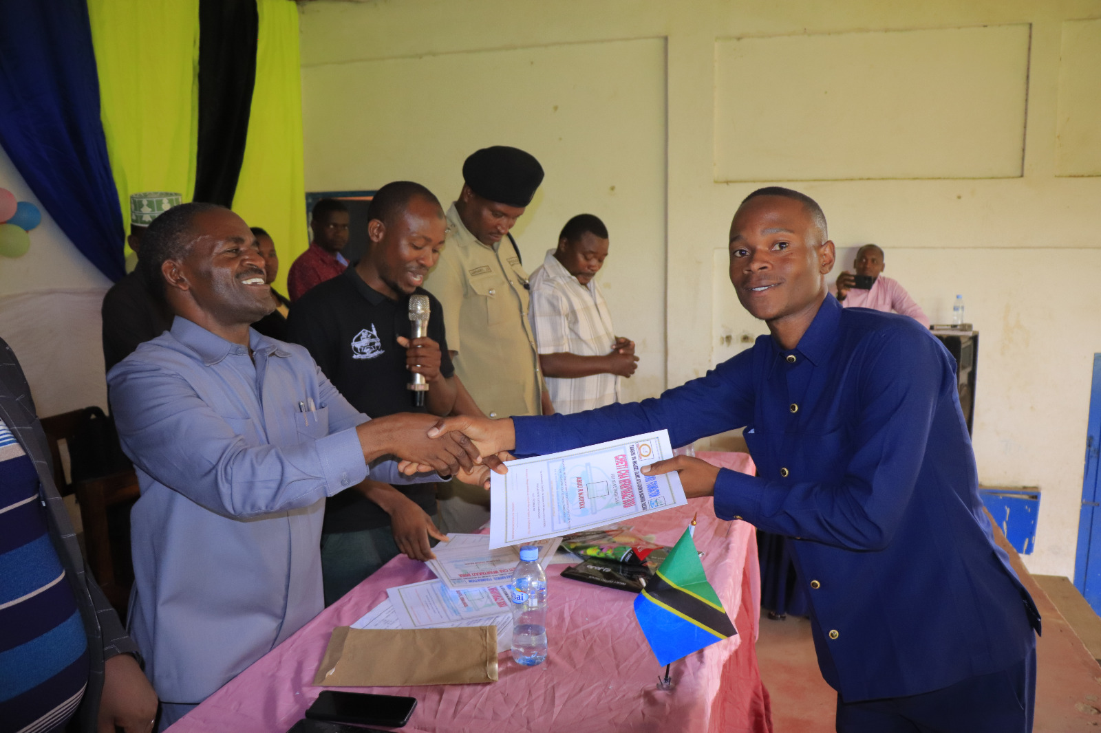 Photos of Mafanikio Foundation volunteers receiving certificates of honor from the Regional Education Officer of Tabora, Mr. Juma Japhet Kaponda, on behalf of the Regional Commissioner of Tabora, for successfully ensuring that all primary school graduates receive special training. Additionally, they launched the campaign "No Child Left Behind - Quality Education for All